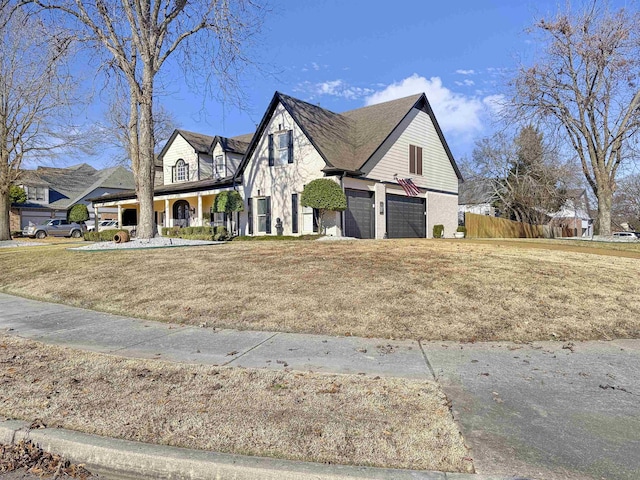 view of front of property with covered porch, a garage, and a front lawn