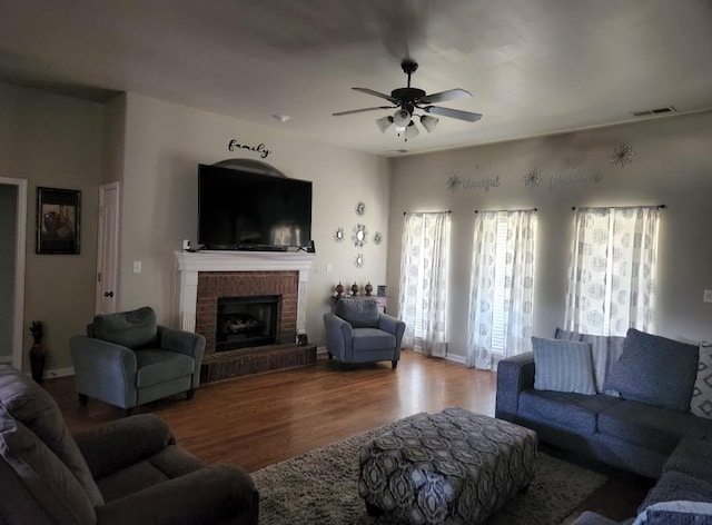 living room featuring ceiling fan, hardwood / wood-style floors, and a brick fireplace