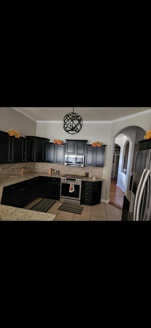 kitchen with backsplash, light tile patterned floors, pendant lighting, and appliances with stainless steel finishes