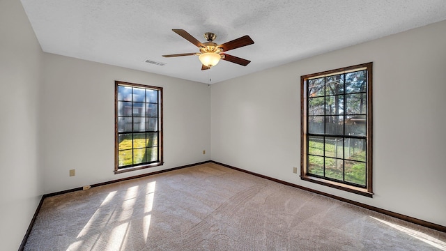 spare room featuring a textured ceiling, ceiling fan, and light carpet