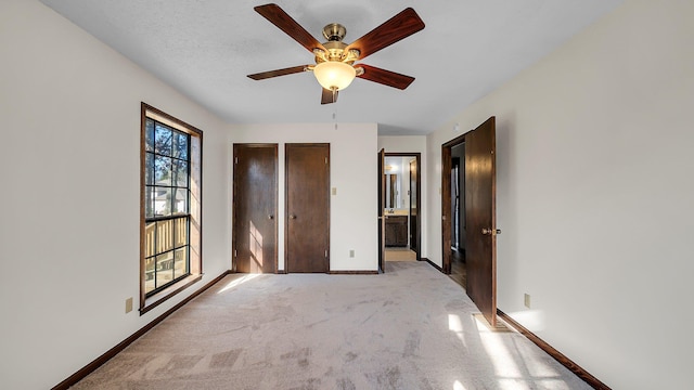 unfurnished bedroom featuring ensuite bath, ceiling fan, and light carpet