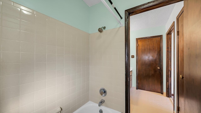 bathroom featuring a textured ceiling and tiled shower / bath combo