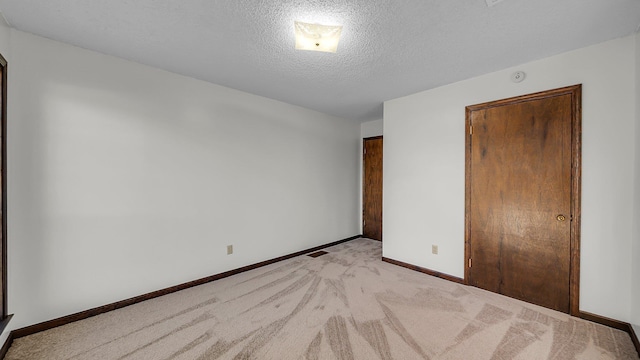 unfurnished bedroom featuring light carpet and a textured ceiling