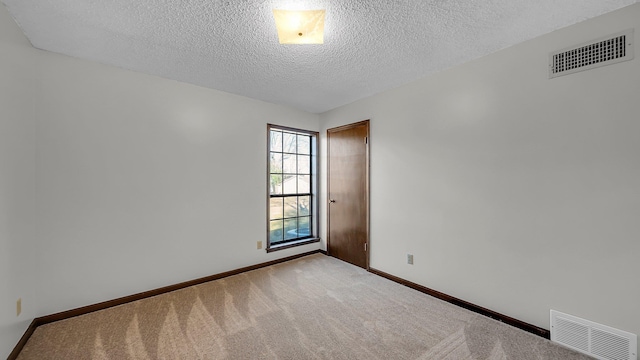 carpeted empty room featuring a textured ceiling