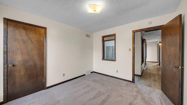 unfurnished bedroom featuring a closet, light colored carpet, and a textured ceiling