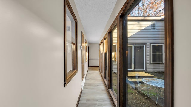 corridor featuring light hardwood / wood-style floors and a textured ceiling