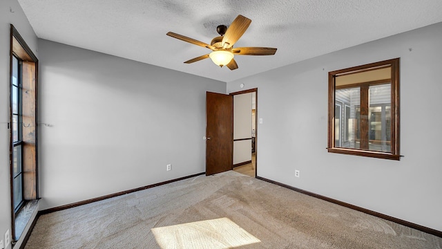 unfurnished room with light carpet, ceiling fan, and a textured ceiling