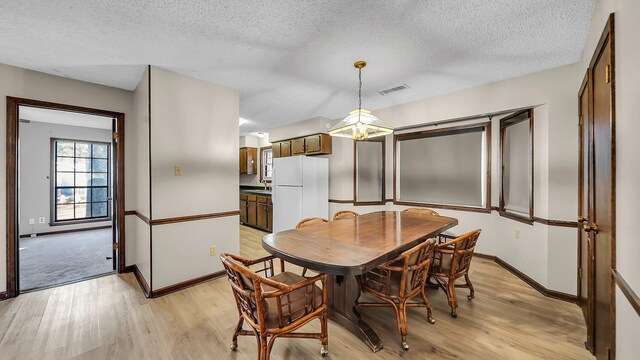 dining area featuring a textured ceiling, light hardwood / wood-style floors, and sink