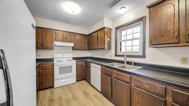 kitchen featuring a textured ceiling, white appliances, light hardwood / wood-style floors, and sink