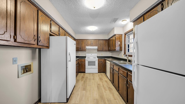 kitchen with a textured ceiling, white appliances, sink, and light hardwood / wood-style flooring