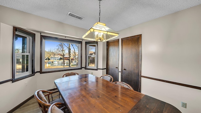 dining area with wood-type flooring and a textured ceiling