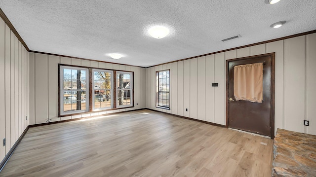 unfurnished room featuring a textured ceiling, light hardwood / wood-style flooring, and ornamental molding