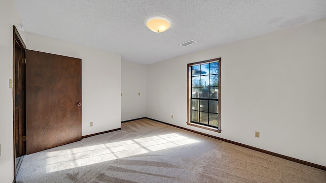 unfurnished room featuring light carpet and a textured ceiling