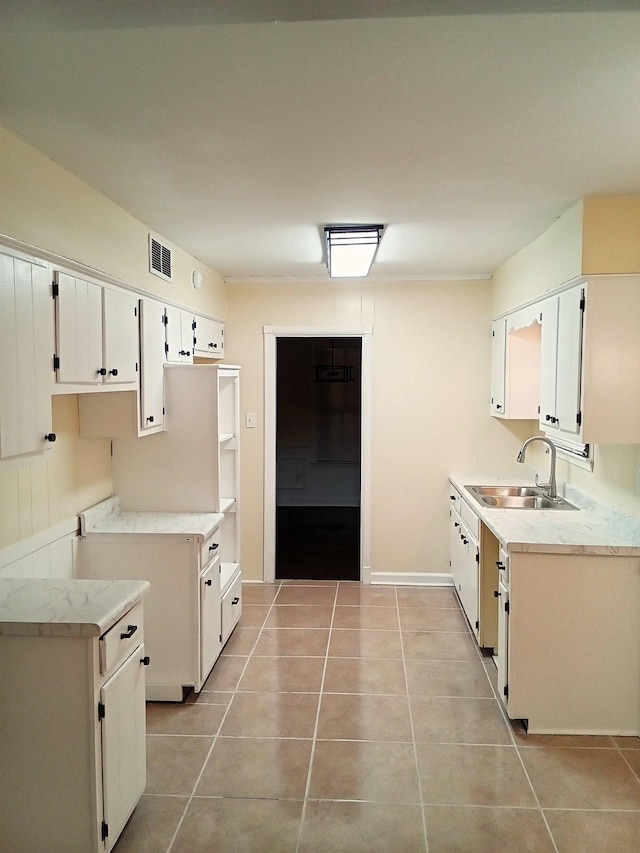 kitchen featuring white cabinetry, sink, and light tile patterned floors