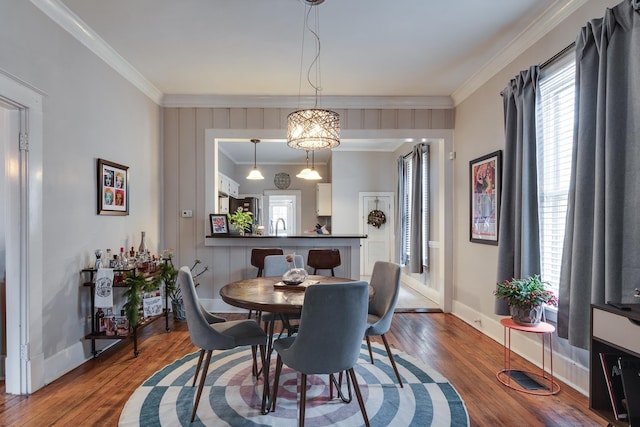 dining room with sink, wood-type flooring, and crown molding