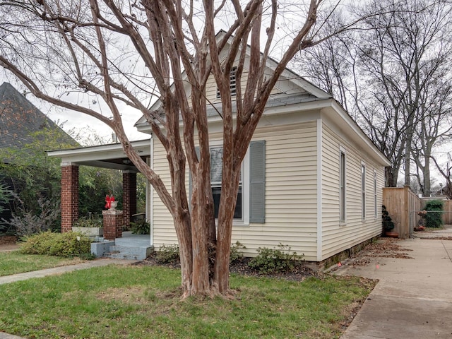 view of side of home featuring fence and a yard