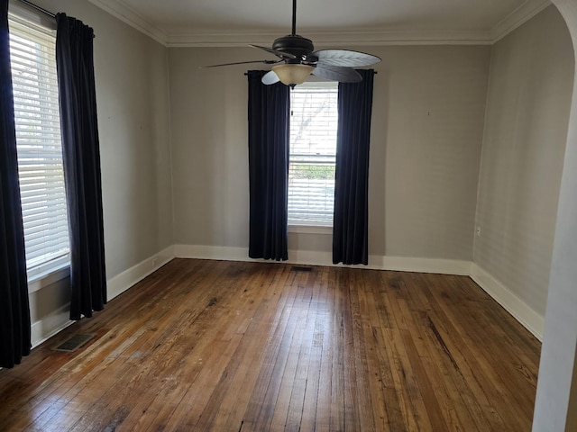 unfurnished room featuring dark wood-style floors, arched walkways, crown molding, and baseboards