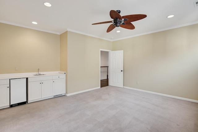 carpeted spare room featuring ceiling fan, ornamental molding, and sink