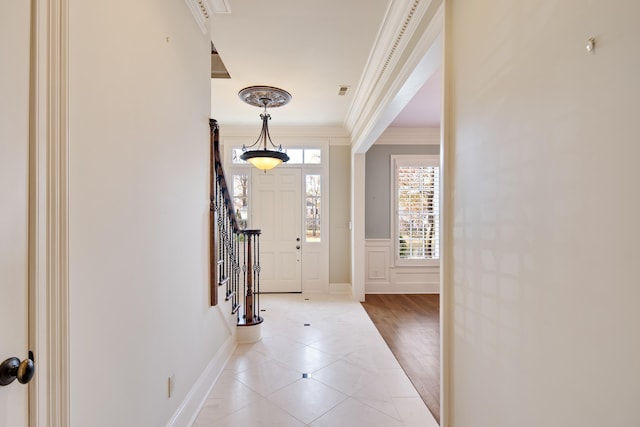 entryway with ornamental molding and light tile patterned flooring