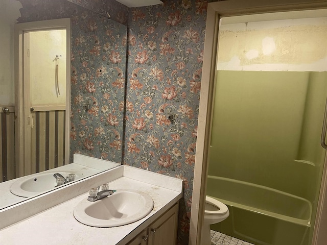 bathroom with vanity, toilet, and wallpapered walls