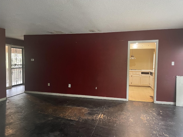 spare room with a textured ceiling and baseboards