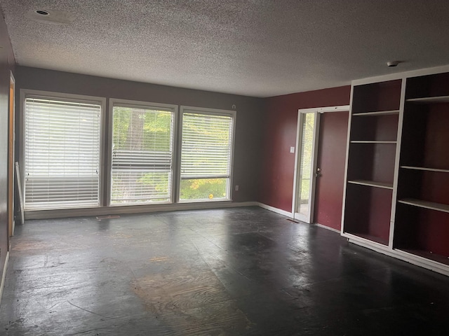 spare room featuring a textured ceiling and baseboards