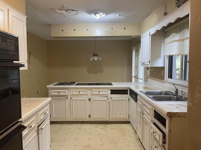 kitchen with pendant lighting, light floors, light countertops, a sink, and black appliances