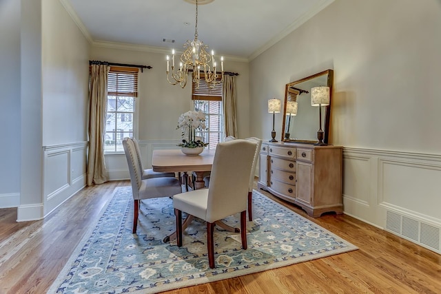 dining space featuring a notable chandelier, light hardwood / wood-style floors, and crown molding