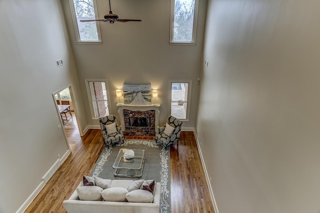 living room featuring a high ceiling, ceiling fan, a healthy amount of sunlight, and a premium fireplace