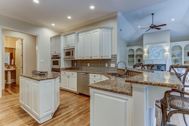 kitchen with kitchen peninsula, appliances with stainless steel finishes, decorative backsplash, sink, and stone counters