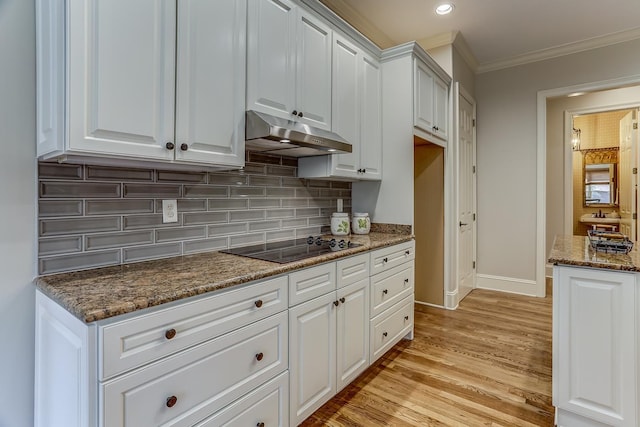 kitchen featuring light hardwood / wood-style flooring, dark stone countertops, crown molding, black electric stovetop, and white cabinets