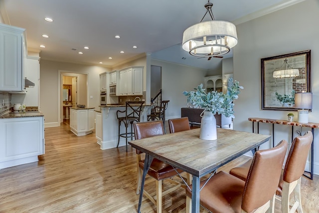 dining room with a chandelier, light wood-type flooring, and crown molding