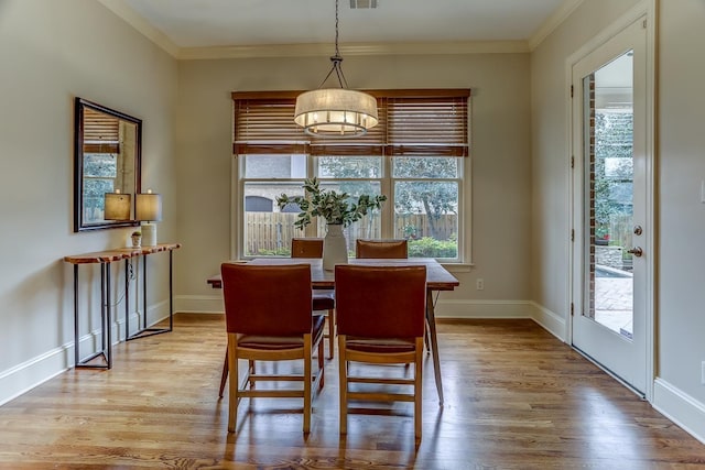 dining area with light hardwood / wood-style flooring and ornamental molding