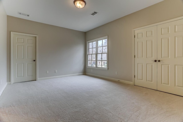 unfurnished bedroom featuring light carpet and a closet