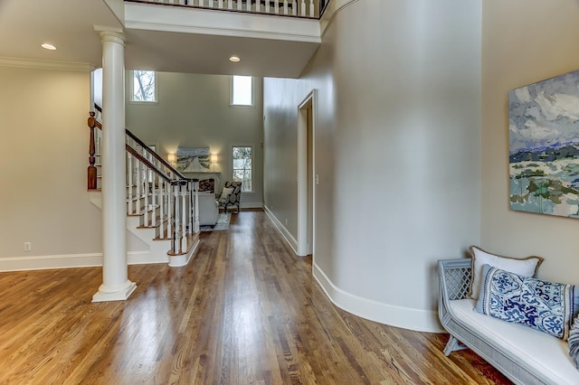 entrance foyer with a high ceiling, decorative columns, hardwood / wood-style flooring, and crown molding