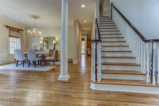 interior space with ornate columns, crown molding, hardwood / wood-style floors, and a notable chandelier