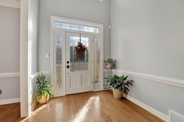 entryway with wood-type flooring and crown molding