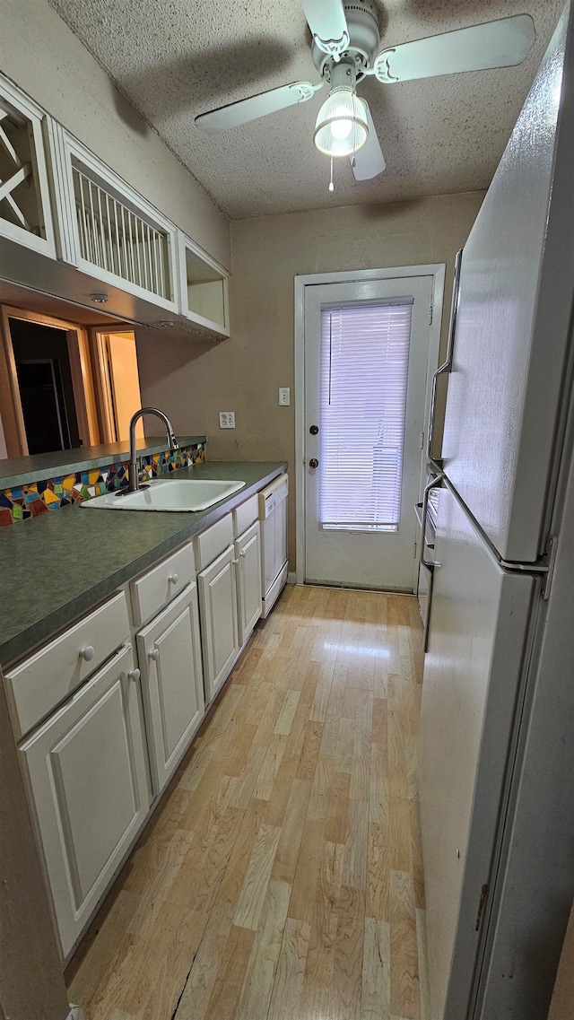 kitchen featuring a textured ceiling, white appliances, sink, light hardwood / wood-style flooring, and white cabinets