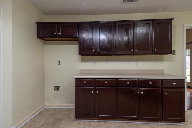 kitchen featuring dark brown cabinetry, a textured ceiling, and light tile patterned floors