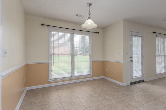 unfurnished dining area featuring light tile patterned floors and a textured ceiling