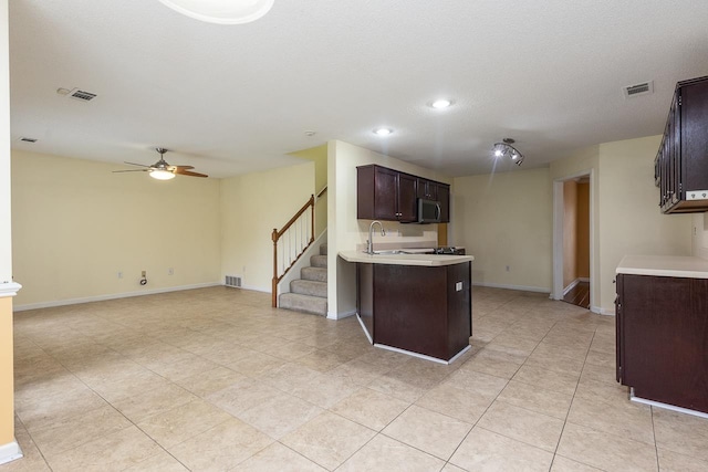 kitchen featuring kitchen peninsula, sink, ceiling fan, light tile patterned flooring, and dark brown cabinetry