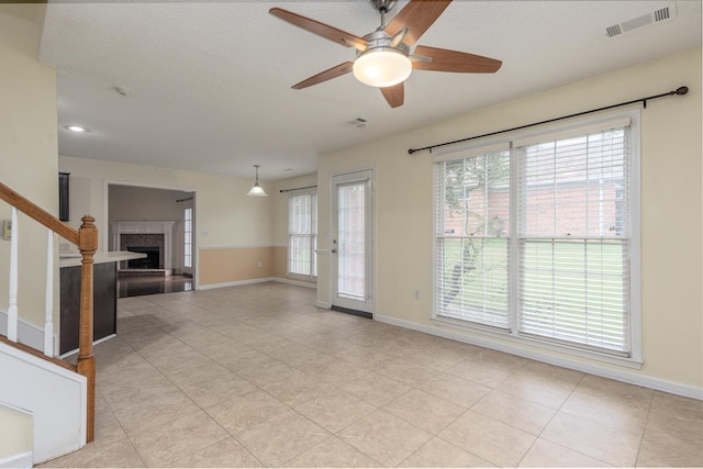 unfurnished living room with light tile patterned floors, a textured ceiling, and ceiling fan