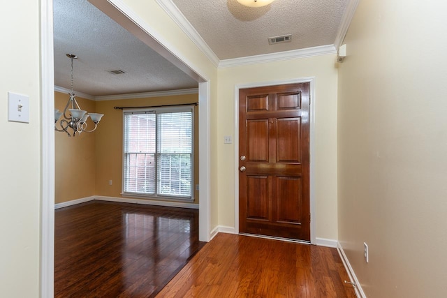 foyer with hardwood / wood-style floors, crown molding, a textured ceiling, and an inviting chandelier