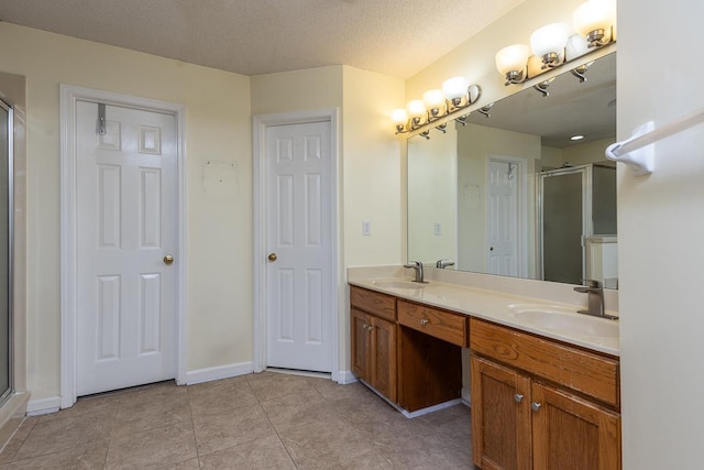 bathroom with vanity, a textured ceiling, tile patterned floors, and a shower with shower door