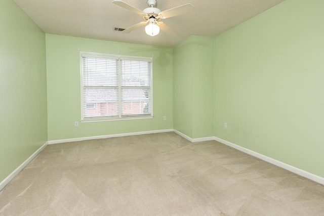 empty room featuring ceiling fan, light carpet, and a textured ceiling