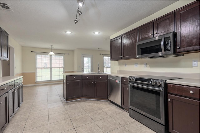 kitchen featuring dark brown cabinetry, sink, hanging light fixtures, kitchen peninsula, and appliances with stainless steel finishes