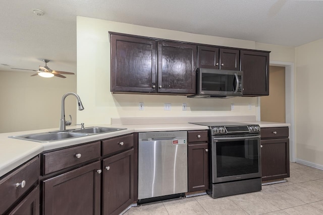 kitchen with appliances with stainless steel finishes, light tile patterned floors, dark brown cabinets, and sink