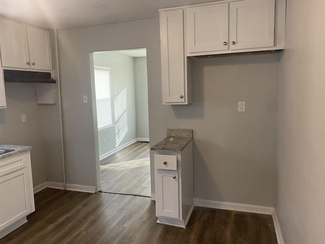 kitchen with stone countertops, white cabinetry, and dark wood-type flooring