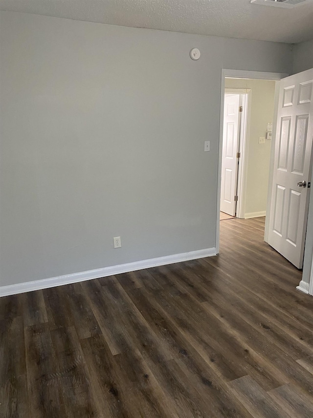 empty room featuring a textured ceiling and dark hardwood / wood-style flooring