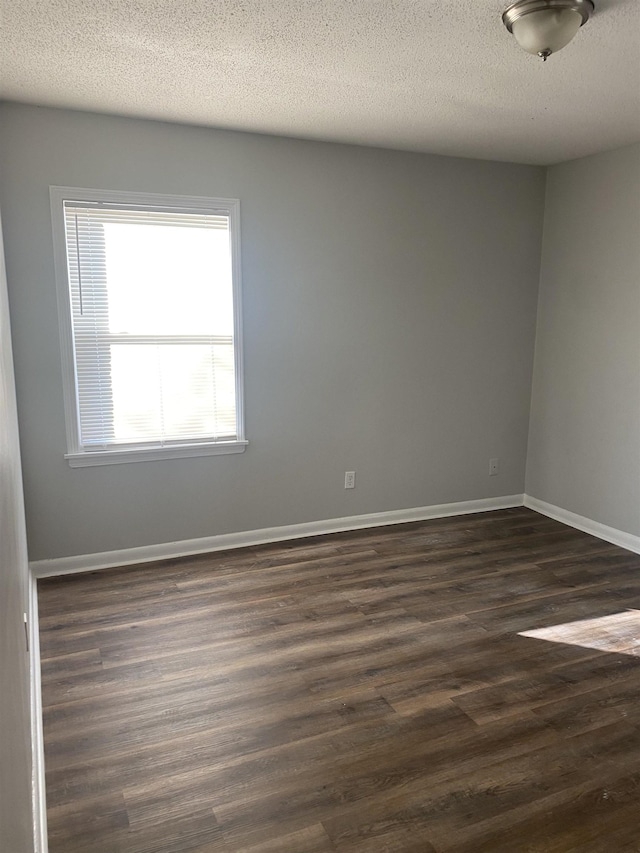 spare room featuring dark hardwood / wood-style flooring and a textured ceiling